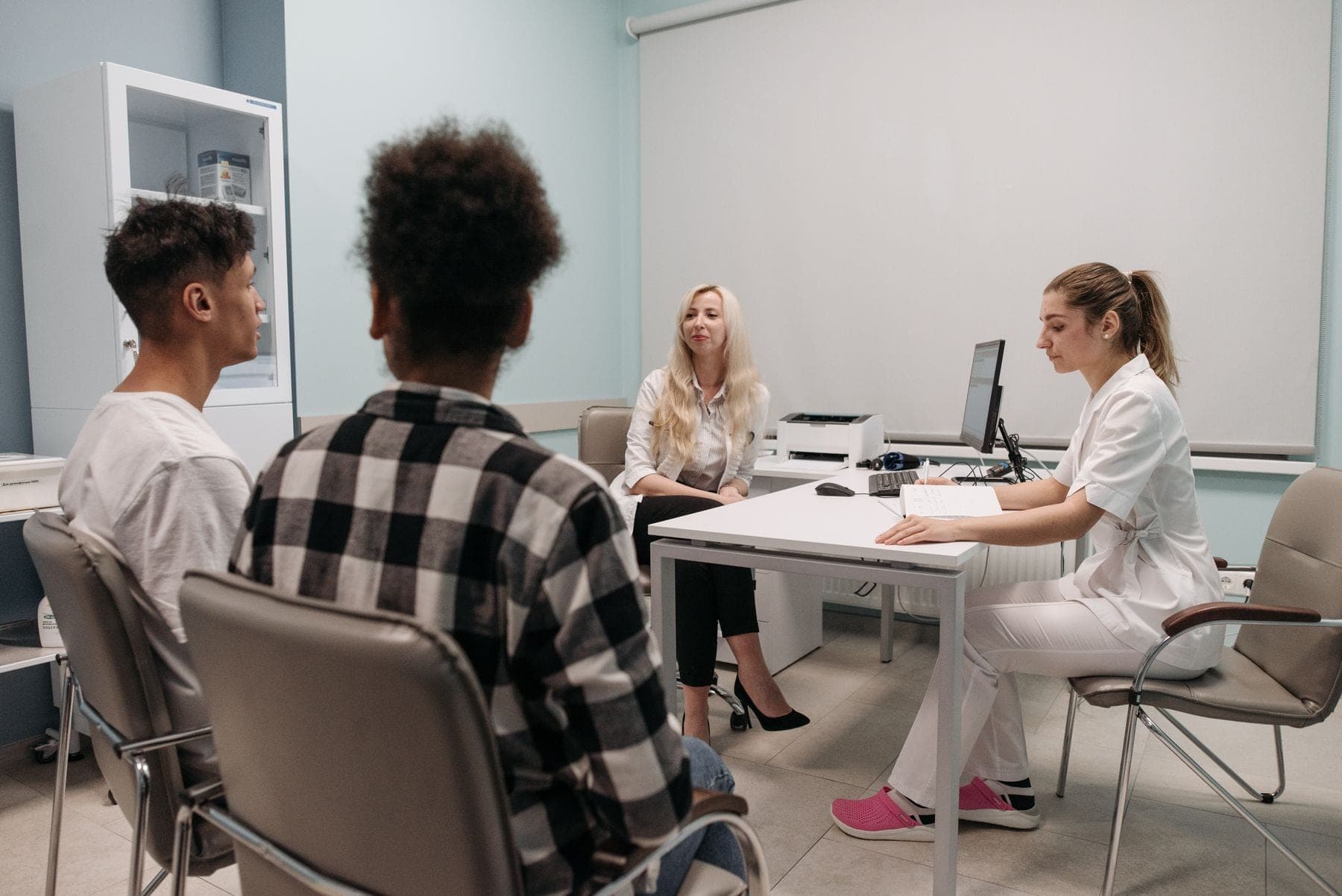 A doctor talks with a teenage patient and parent during an appointment