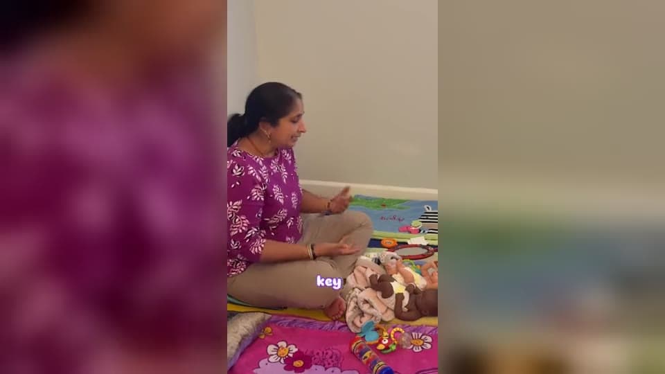 Dr. Viswanadham on a play mat with training dolls, explaining baby massage
