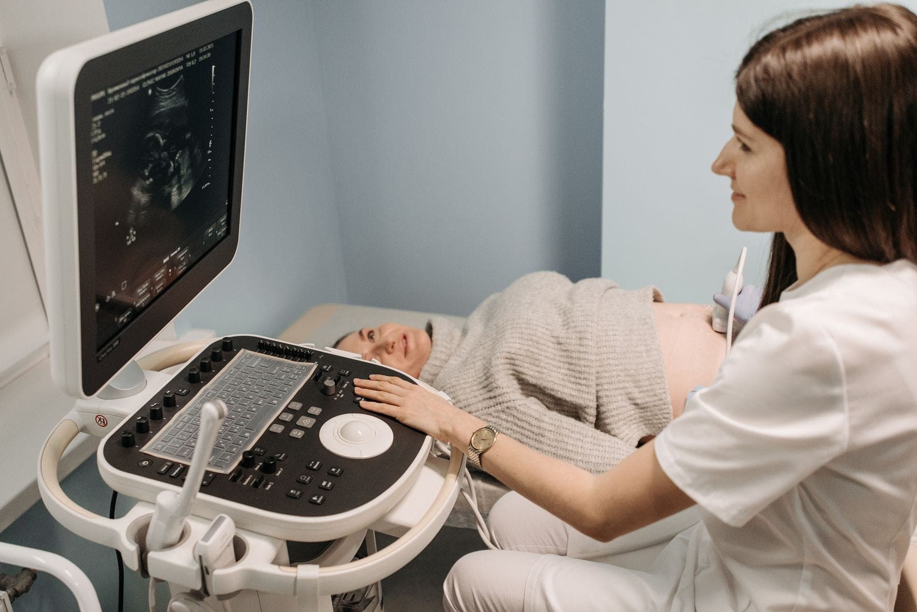 A pregnant woman smiles during an ultrasound with her doctor