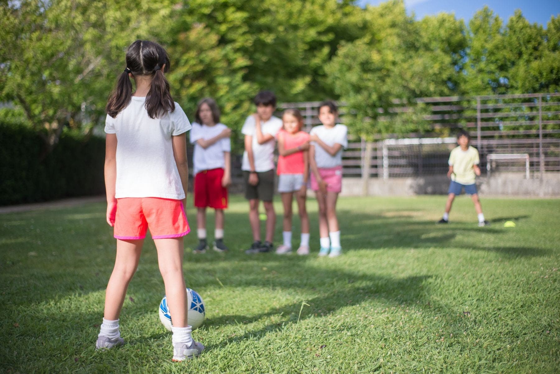 Children play soccer on a sunny green field
